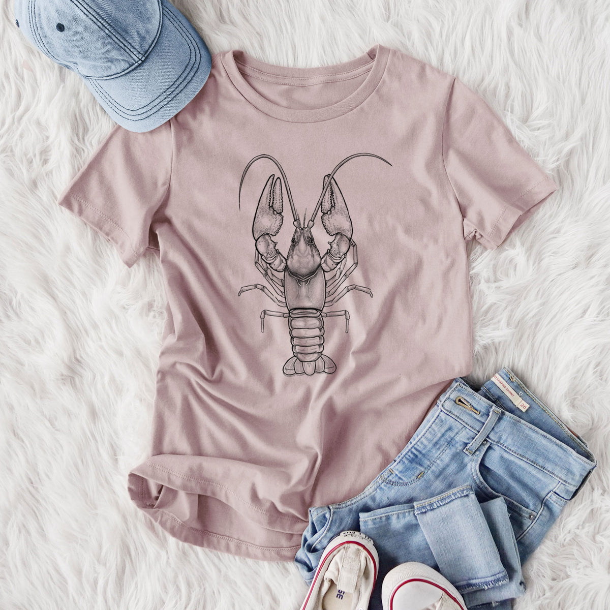 Women's relaxed fit cotton t-shirt printed with a detailed black ink illustration of a crayfish with its claws raised, seen from above, styled flat on a white faux fur rug with jeans.