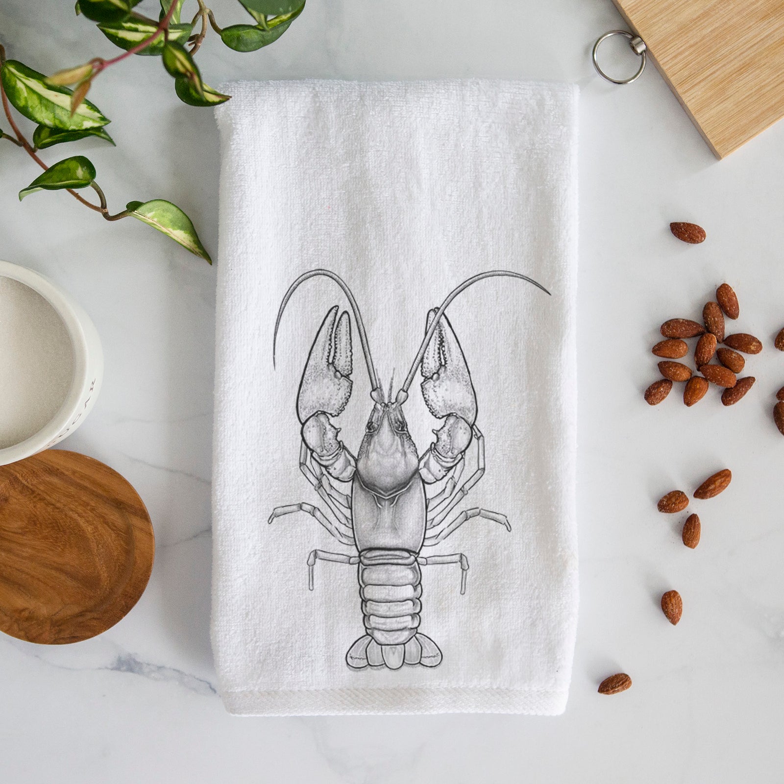 White hand towel printed with a detailed black ink illustration of a crayfish with its claws raised, seen from above.