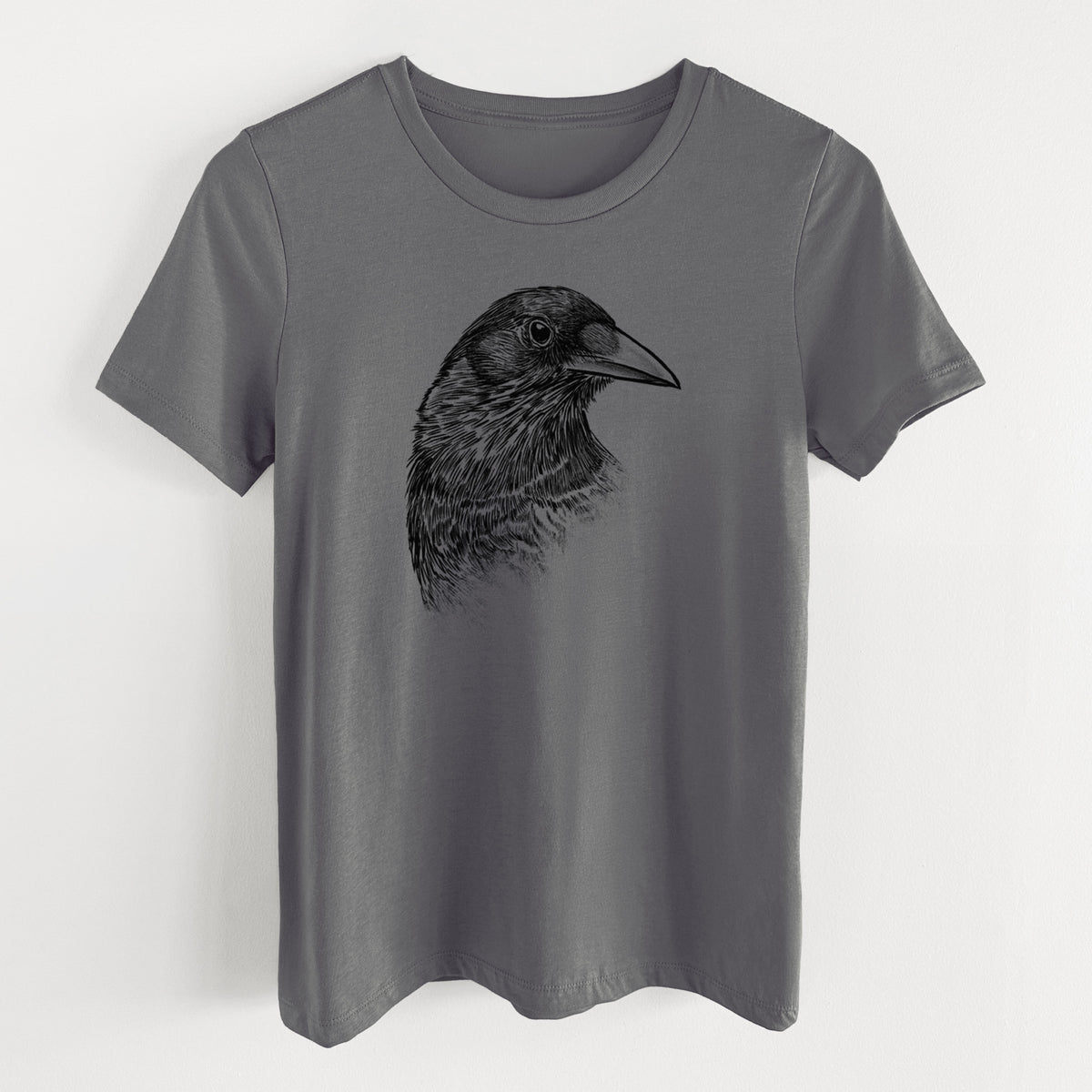 Asphalt women's relaxed fit cotton t-shirt laid flat, printed with a detailed black ink portrait of a crow's head in profile.