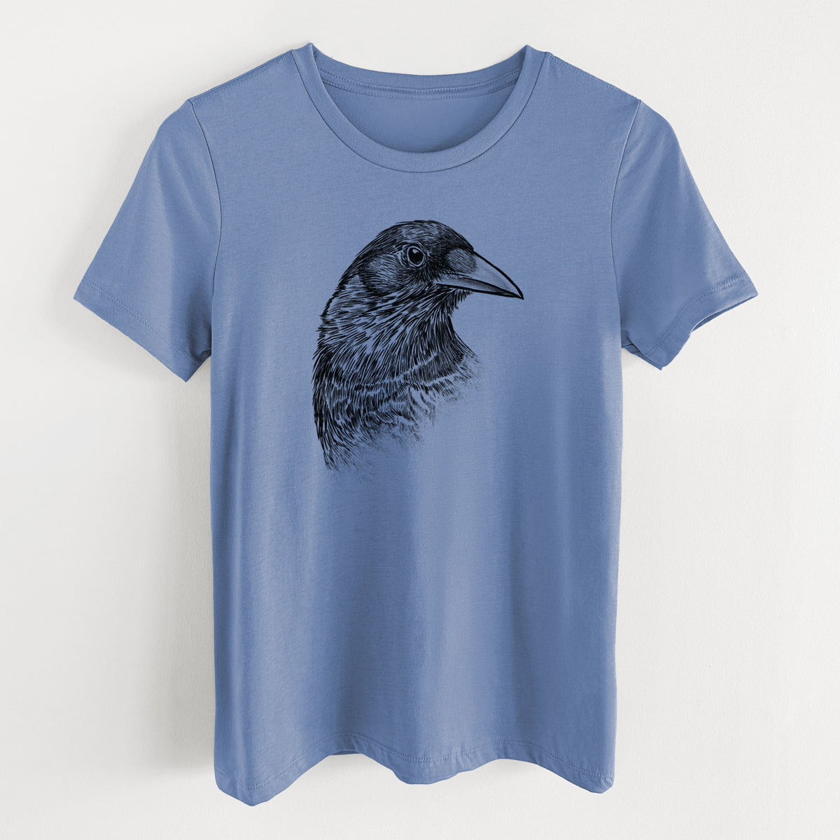 Blue bell women's relaxed fit cotton t-shirt laid flat, printed with a detailed black ink portrait of a crow's head in profile.