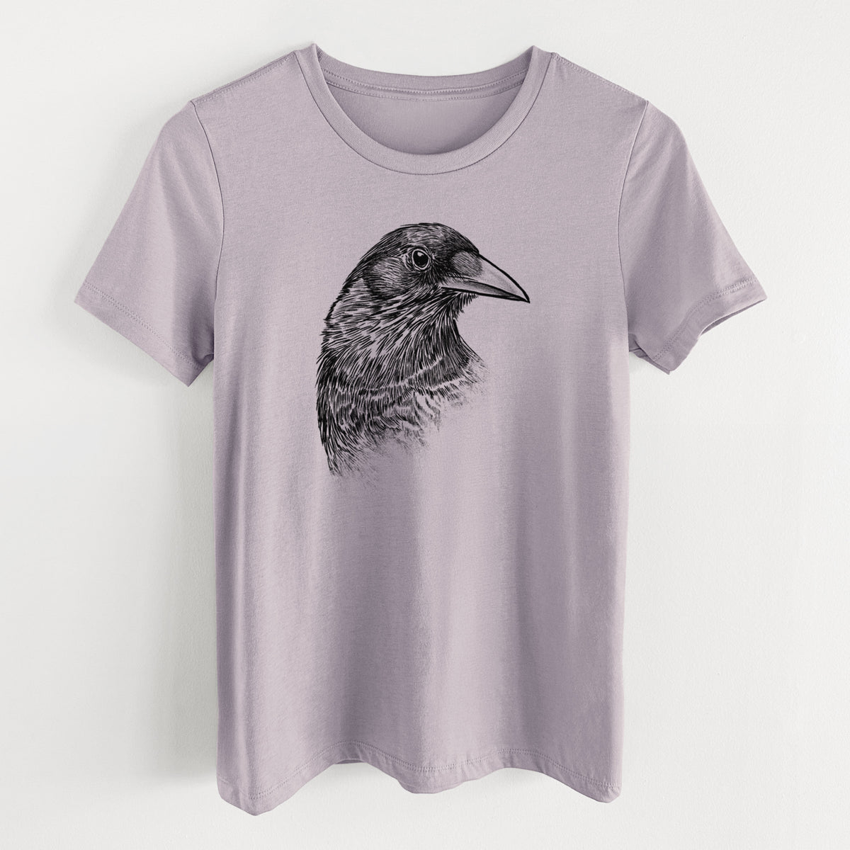Light violet women's relaxed fit cotton t-shirt laid flat, printed with a detailed black ink portrait of a crow's head in profile.