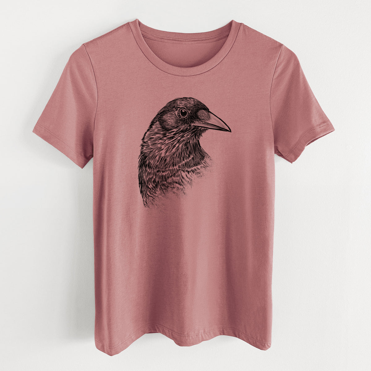 Mauve pink women's relaxed fit cotton t-shirt laid flat, printed with a detailed black ink portrait of a crow's head in profile.