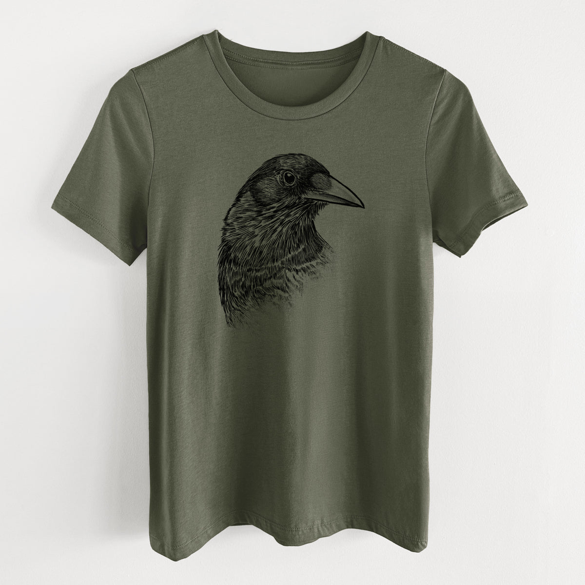 Military green women's relaxed fit cotton t-shirt laid flat, printed with a detailed black ink portrait of a crow's head in profile.