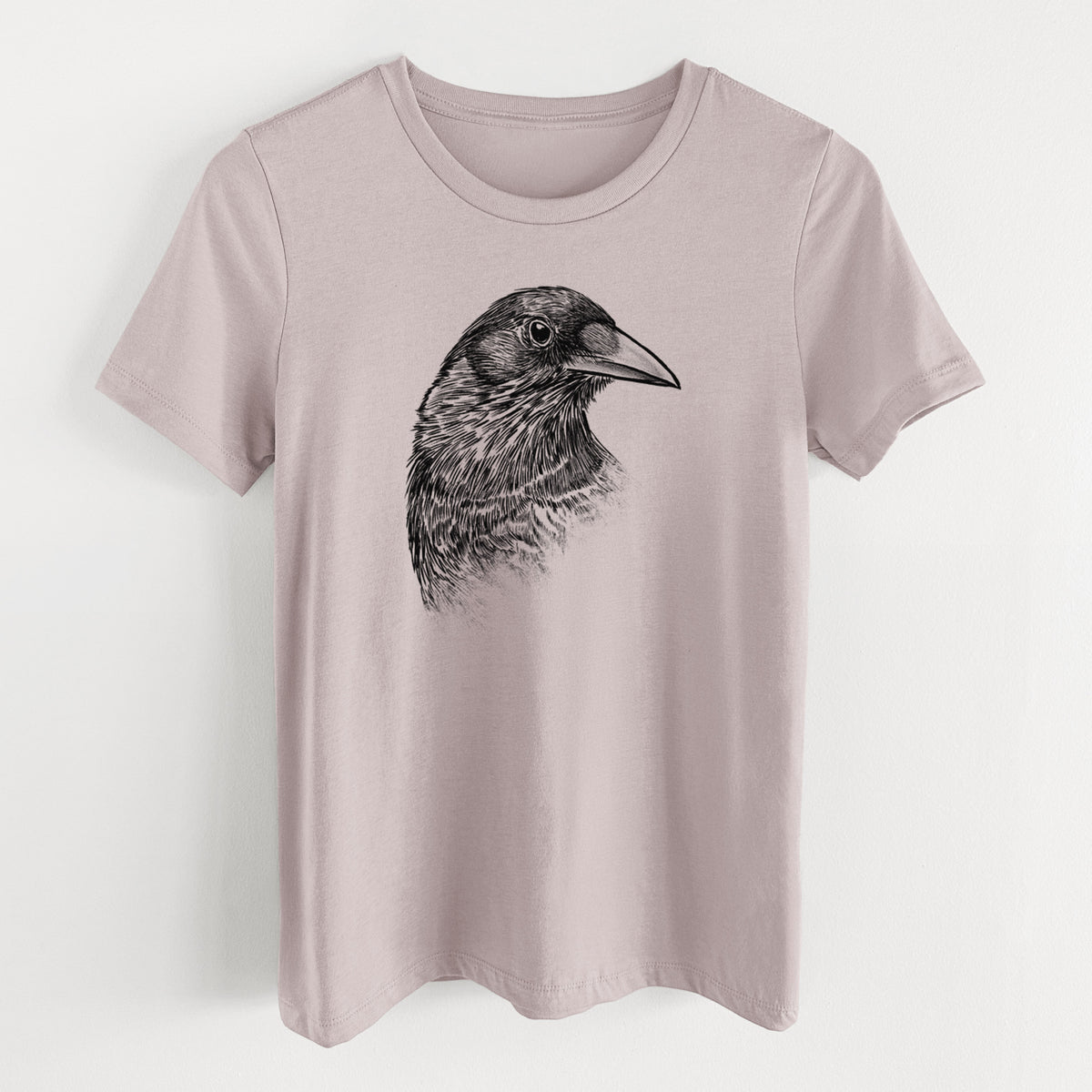 Pink gravel women's relaxed fit cotton t-shirt laid flat, printed with a detailed black ink portrait of a crow's head in profile.