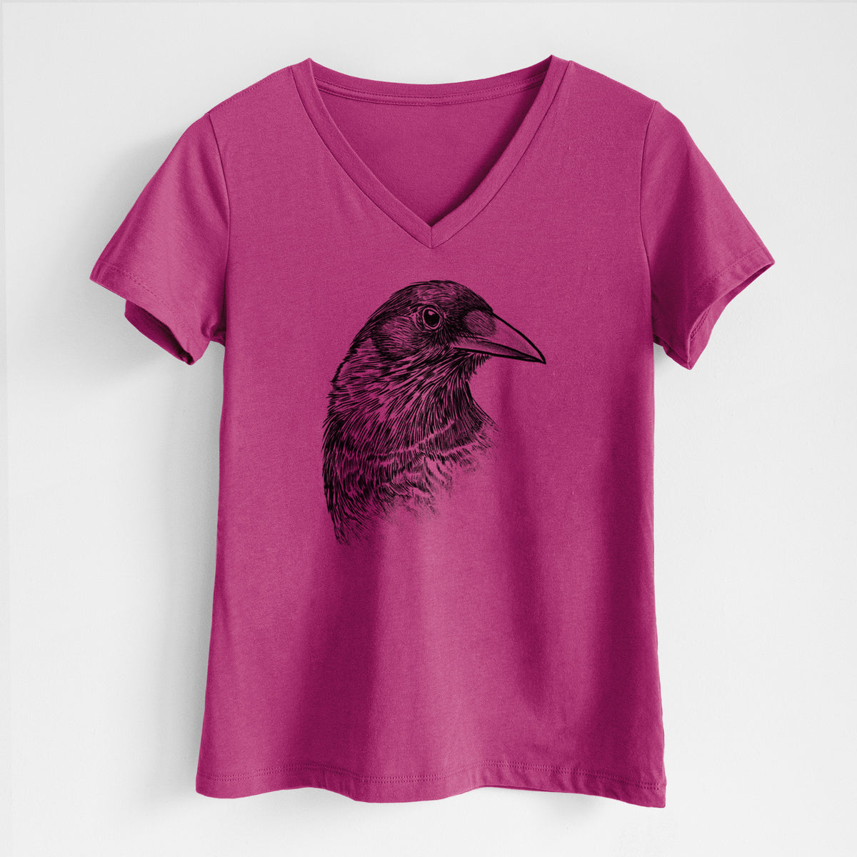 Berry pink women's relaxed fit cotton V-neck t-shirt laid flat, printed with a detailed black ink portrait of a crow's head in profile.