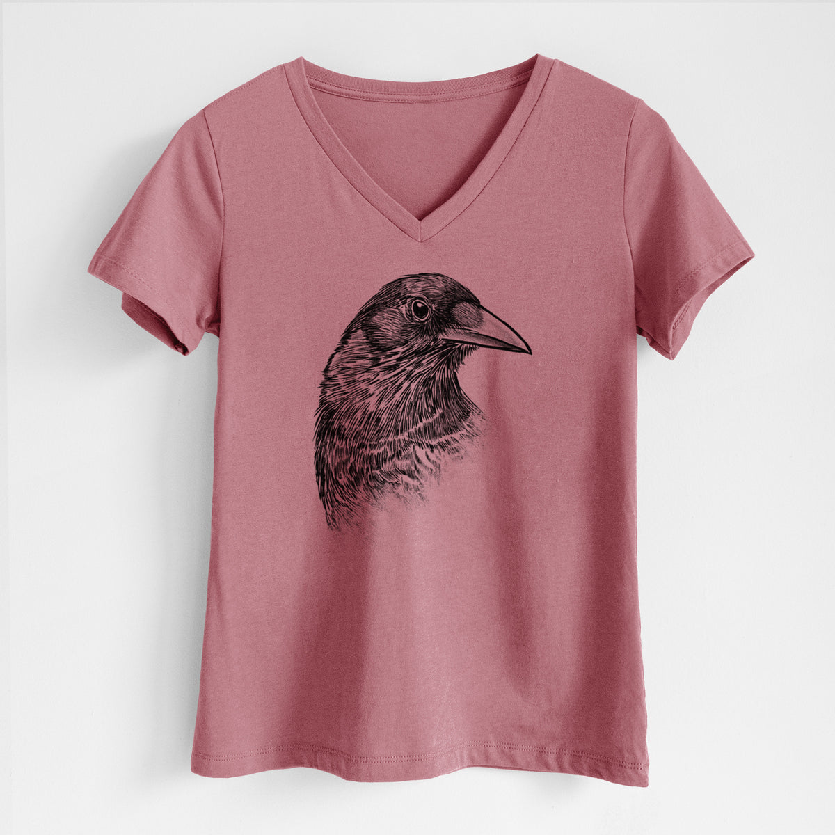 Mauve pink women's relaxed fit cotton V-neck t-shirt laid flat, printed with a detailed black ink portrait of a crow's head in profile.