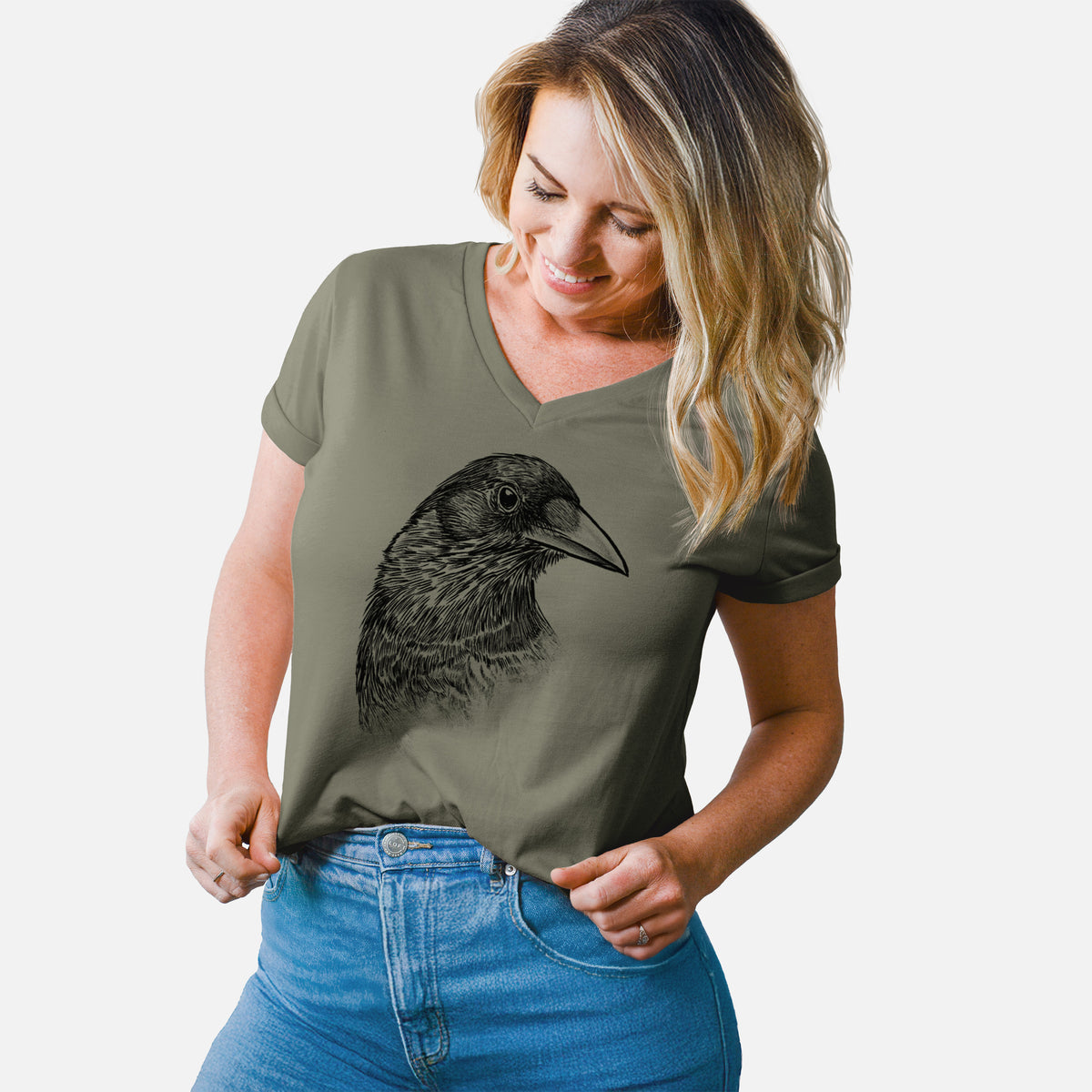 Woman wearing a military green women's relaxed fit cotton V-neck t-shirt printed with a detailed black ink portrait of a crow's head in profile.