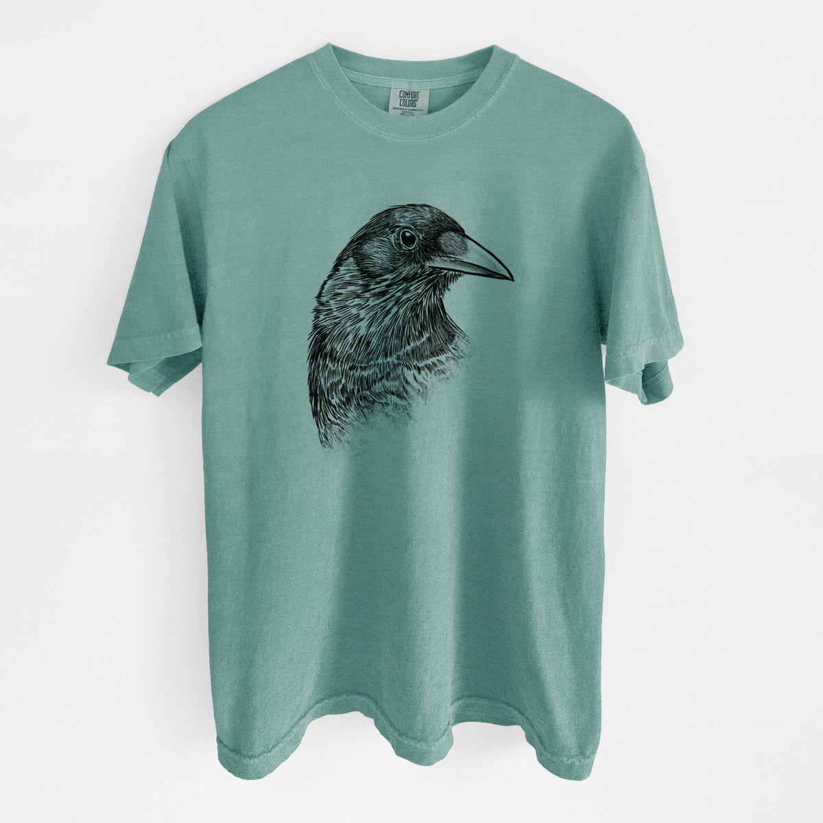 Reef green Comfort Colors t-shirt laid flat, printed with a detailed black ink portrait of a crow's head in profile.