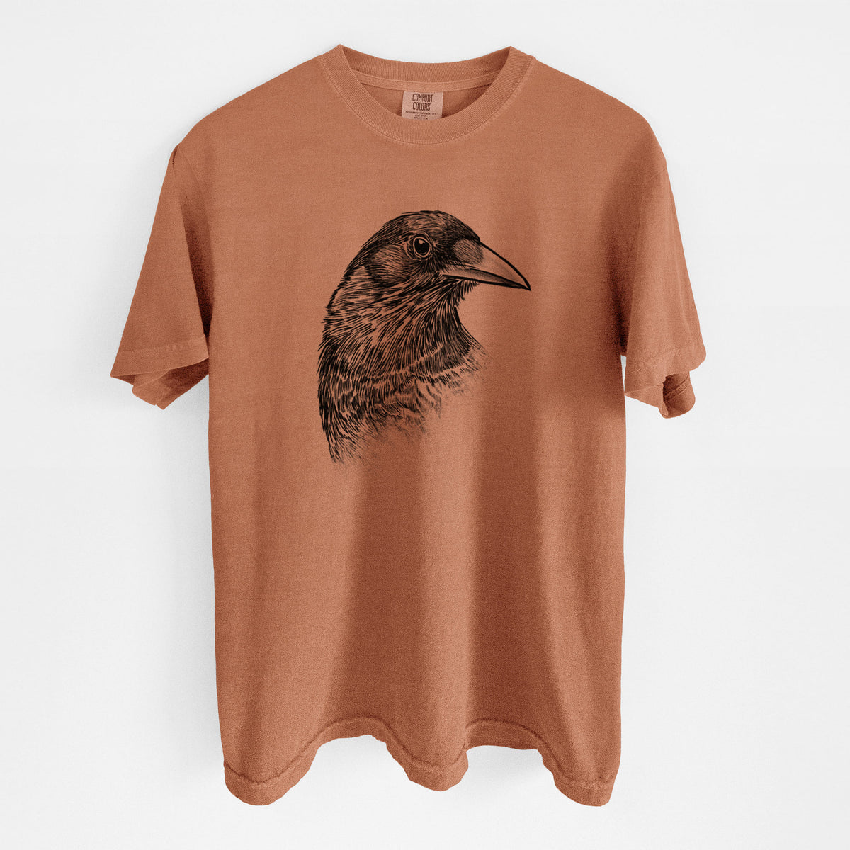 Yam burnt orange Comfort Colors t-shirt laid flat, printed with a detailed black ink portrait of a crow's head in profile.