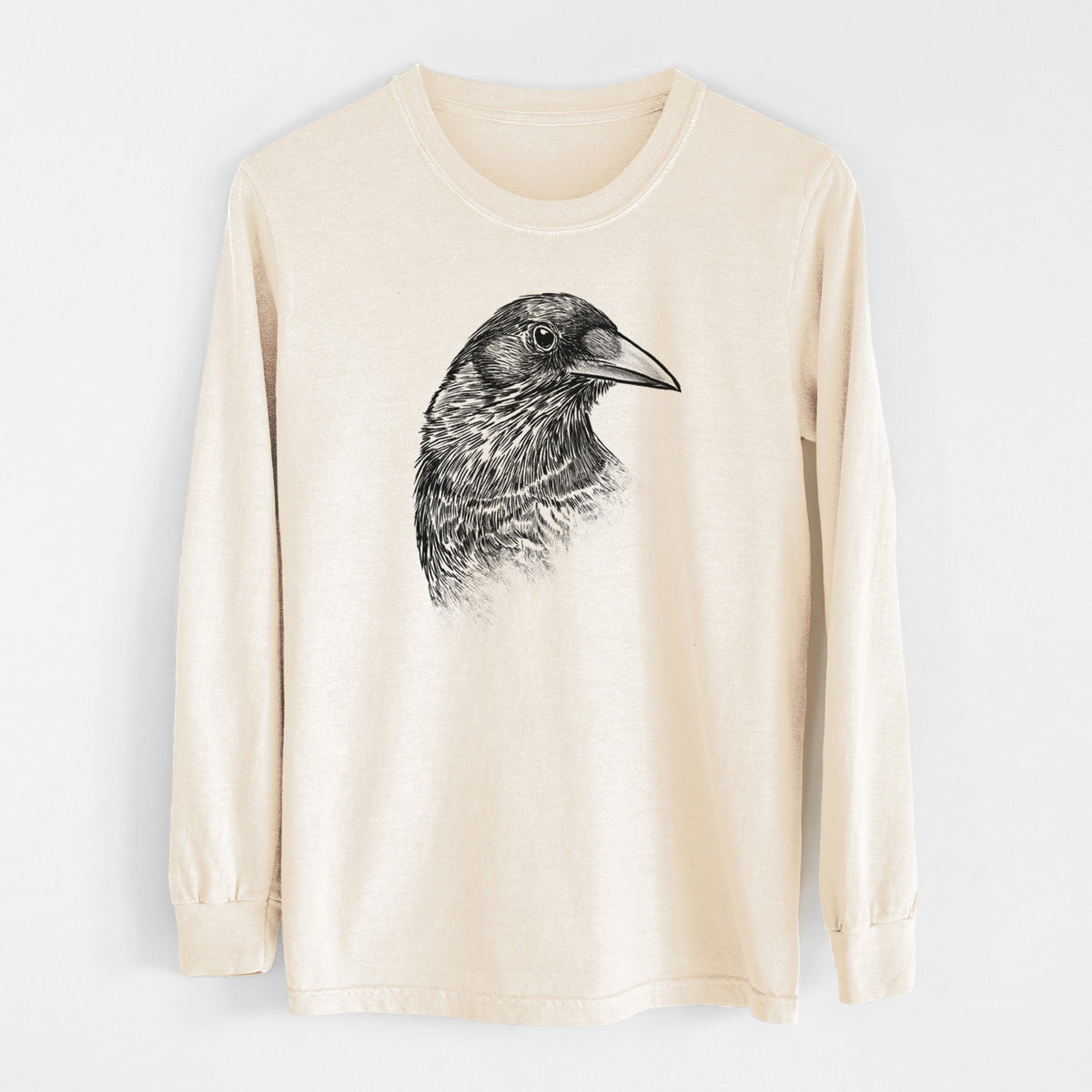 Ivory Comfort Colors long sleeve shirt laid flat, printed with a detailed black ink portrait of a crow's head in profile.