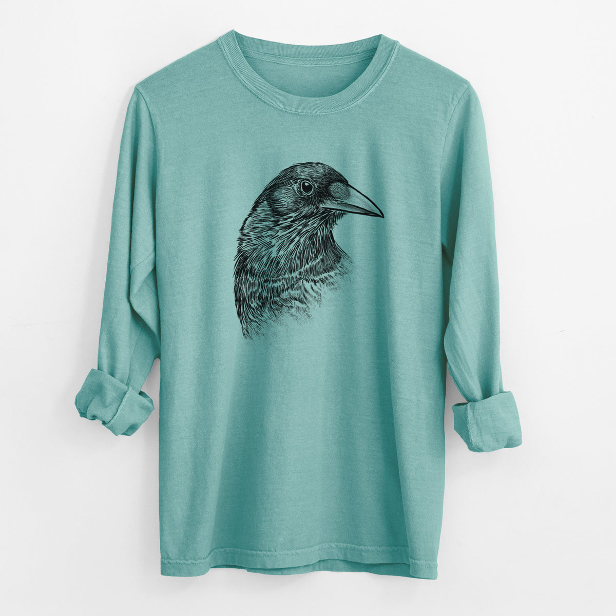 Reef green Comfort Colors long sleeve shirt laid flat with the cuffs rolled, printed with a detailed black ink portrait of a crow's head in profile.