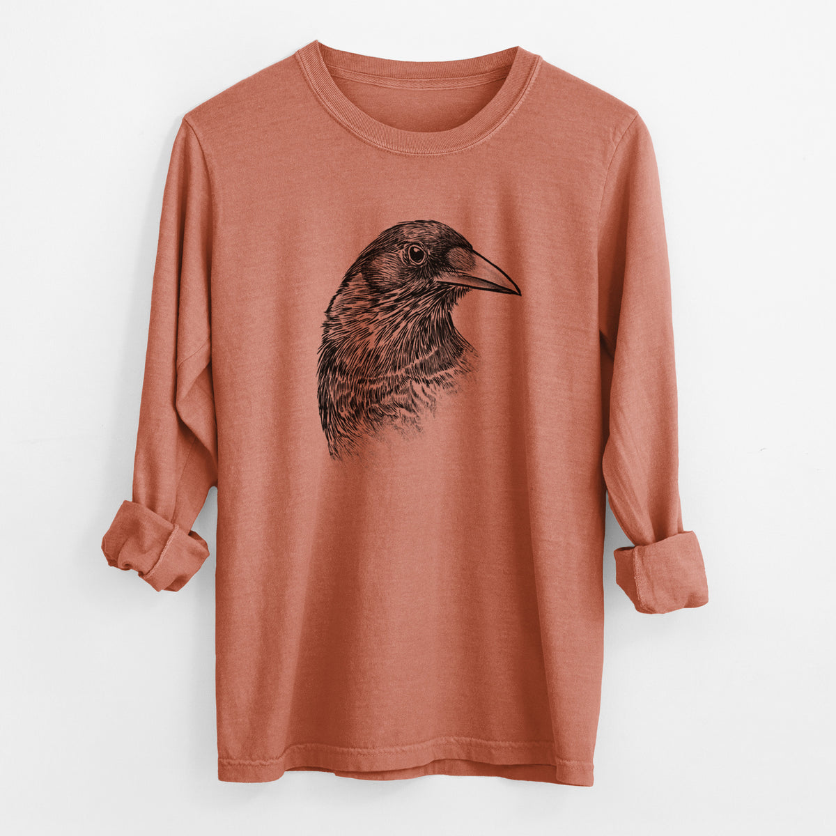 Yam burnt orange Comfort Colors long sleeve shirt laid flat with the cuffs rolled, printed with a detailed black ink portrait of a crow's head in profile.