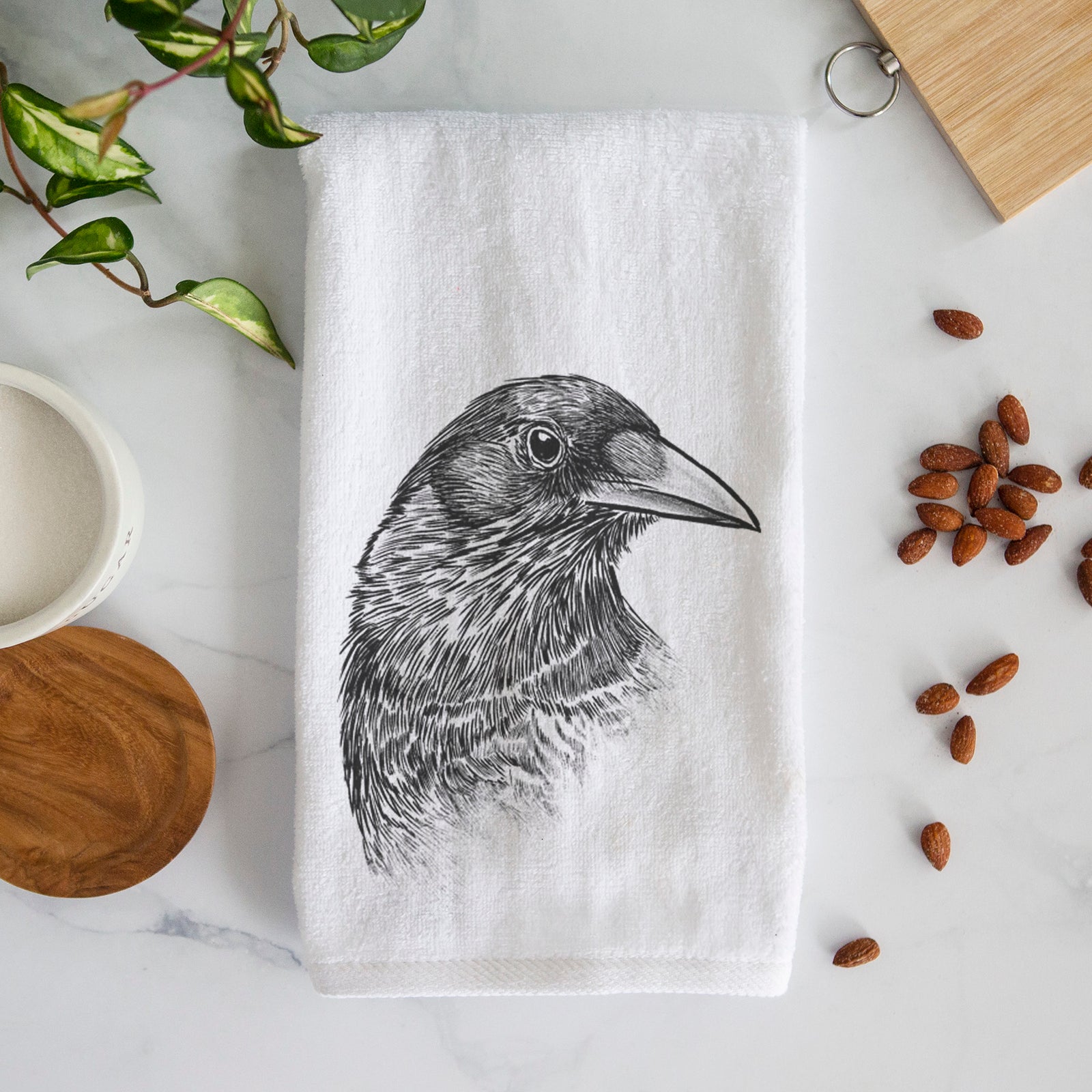 White hand towel printed with a detailed black ink portrait of a crow's head in profile.