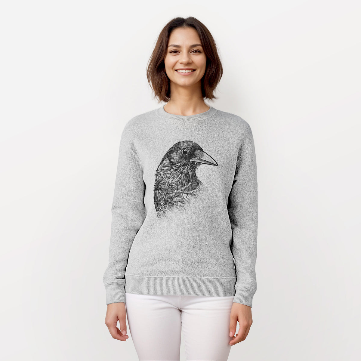 Woman wearing a knit sweatshirt printed with a detailed black ink portrait of a crow's head in profile.