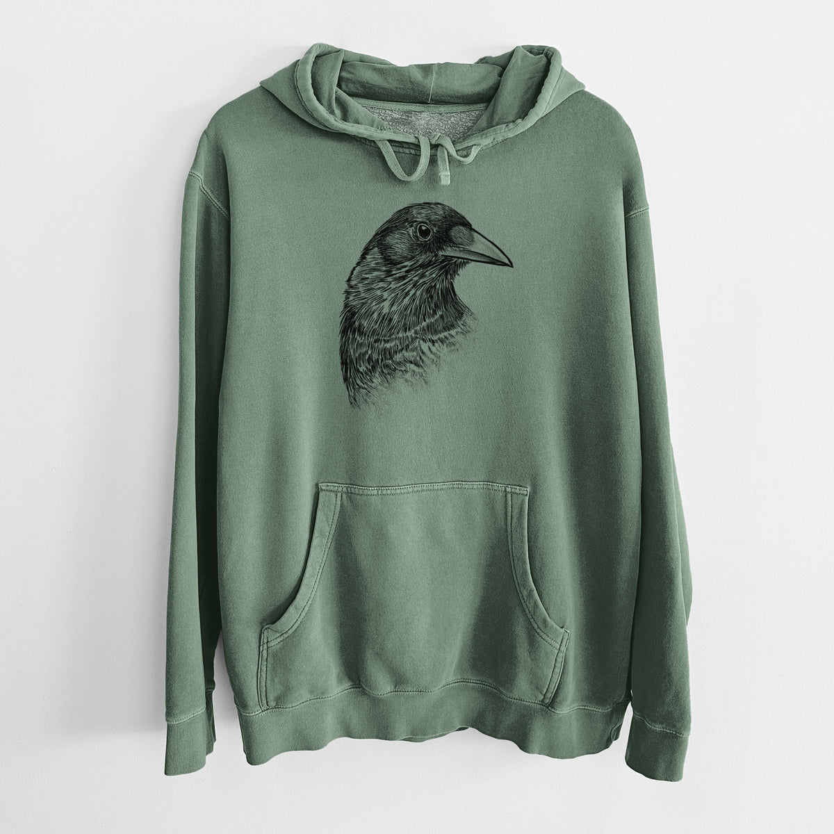 Alpine green pigment dyed hoodie laid flat, printed with a detailed black ink portrait of a crow's head in profile.