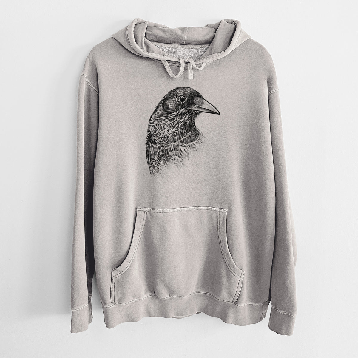 Cement grey pigment dyed hoodie laid flat, printed with a detailed black ink portrait of a crow's head in profile.