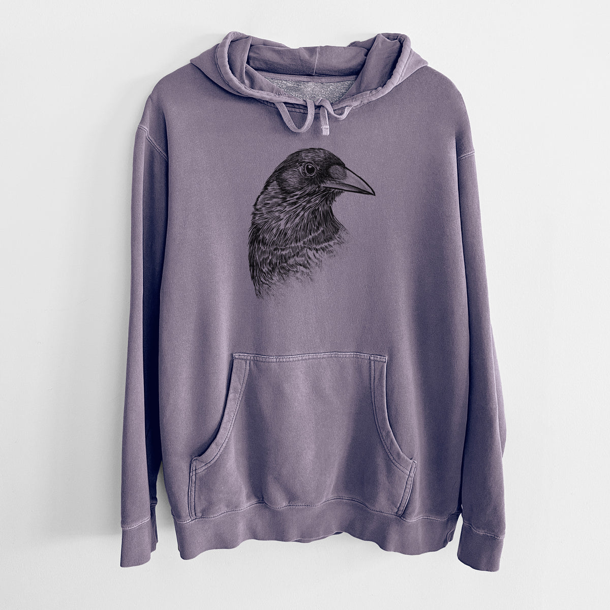 Plum purple pigment dyed hoodie laid flat, printed with a detailed black ink portrait of a crow's head in profile.