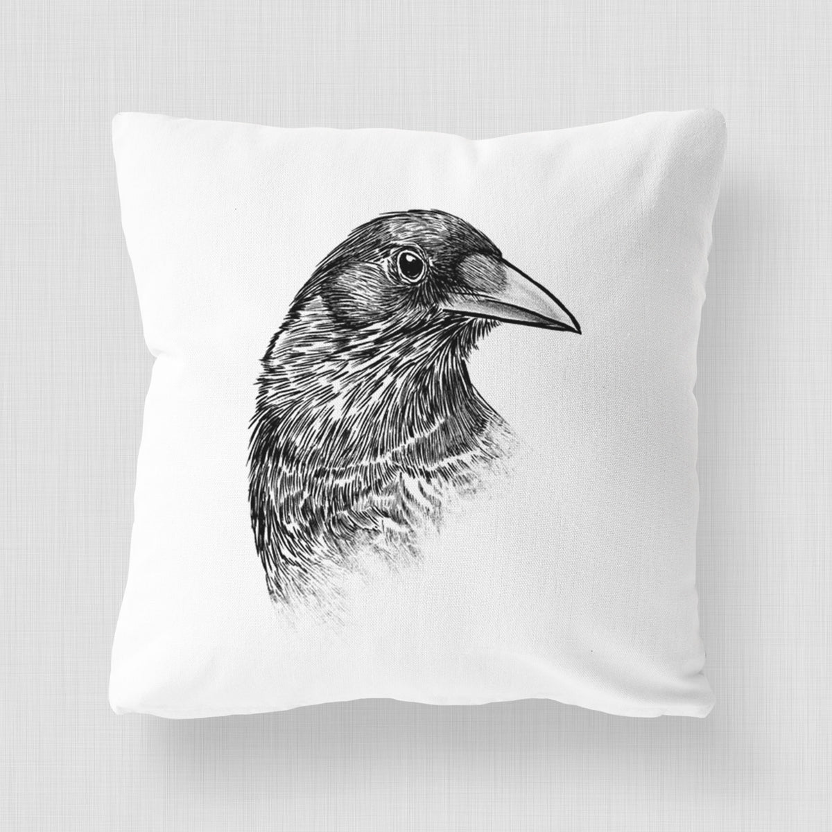 White pillow cover printed with a detailed black ink portrait of a crow's head in profile.