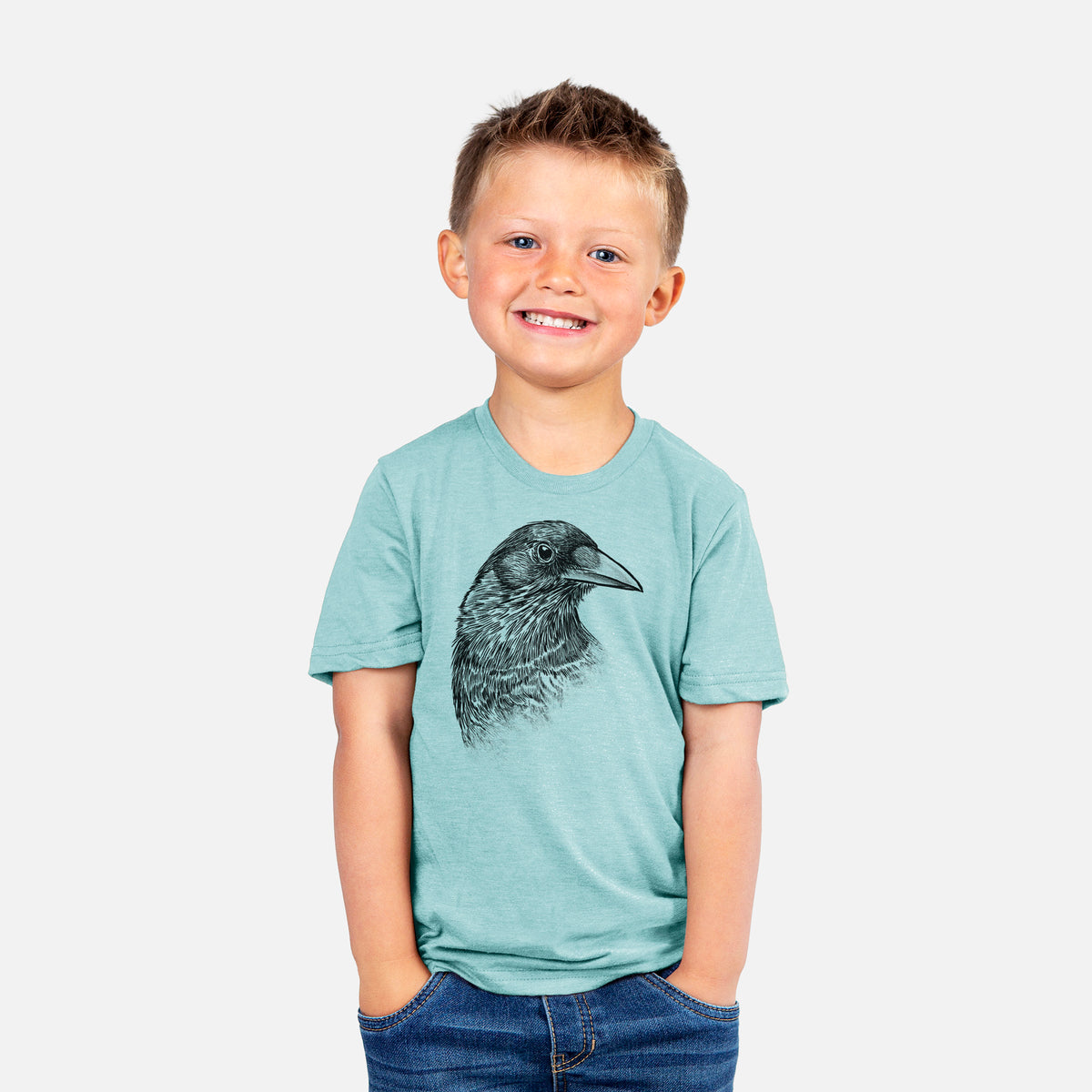 Smiling boy wearing a youth t-shirt printed with a detailed black ink portrait of a crow's head in profile.