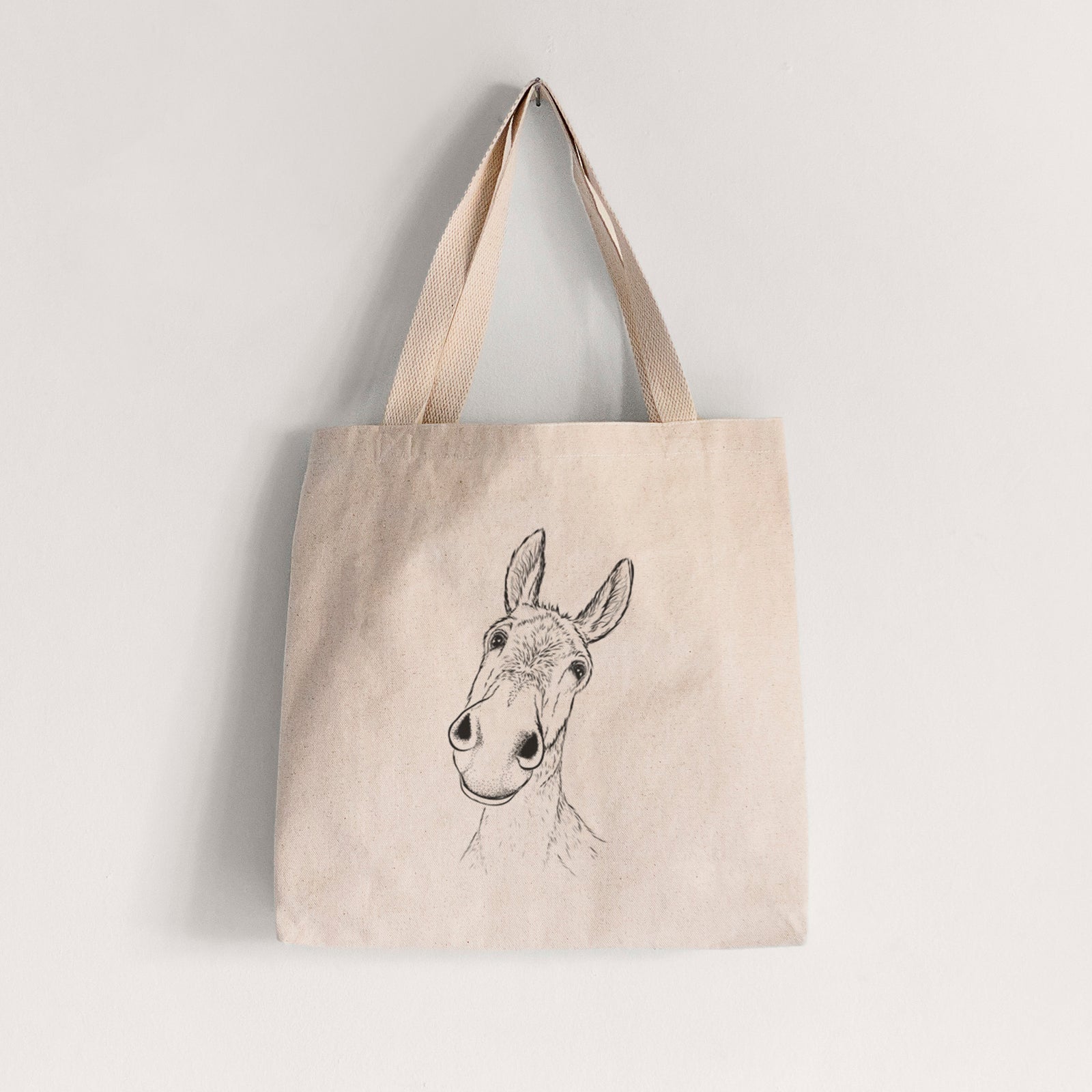 Natural canvas tote bag printed with a black ink illustration of a curious donkey's head with tall ears.