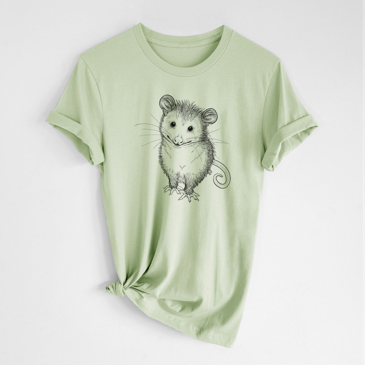 Spring green lightweight cotton t-shirt laid flat with the sleeves rolled, printed with a black ink illustration of a wide-eyed baby opossum sitting.