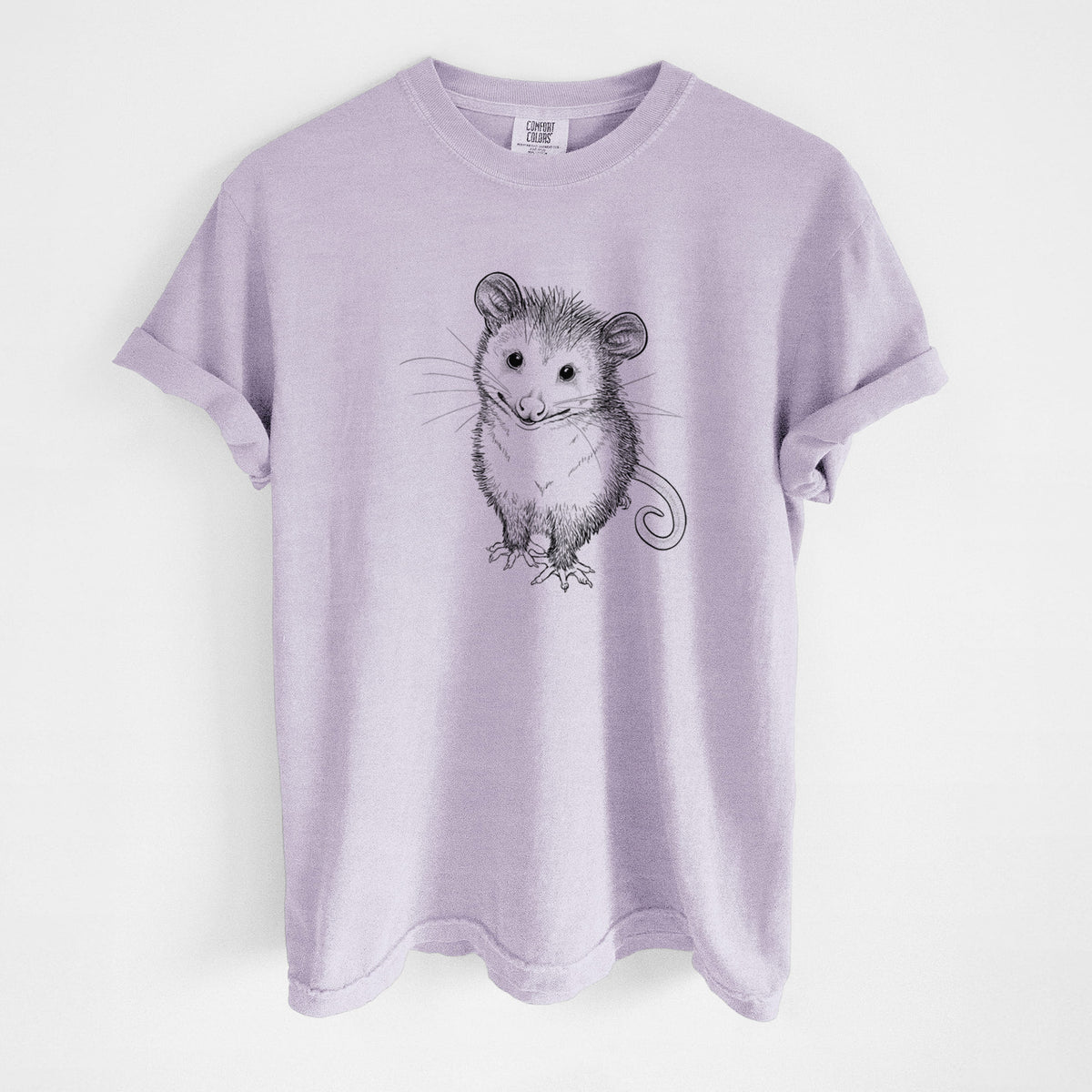 Orchid purple Comfort Colors t-shirt laid flat, printed with a black ink illustration of a wide-eyed baby opossum sitting.