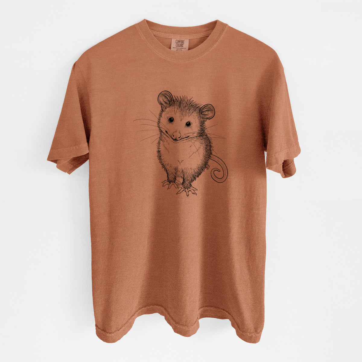 Yam burnt orange Comfort Colors t-shirt laid flat, printed with a black ink illustration of a wide-eyed baby opossum sitting.