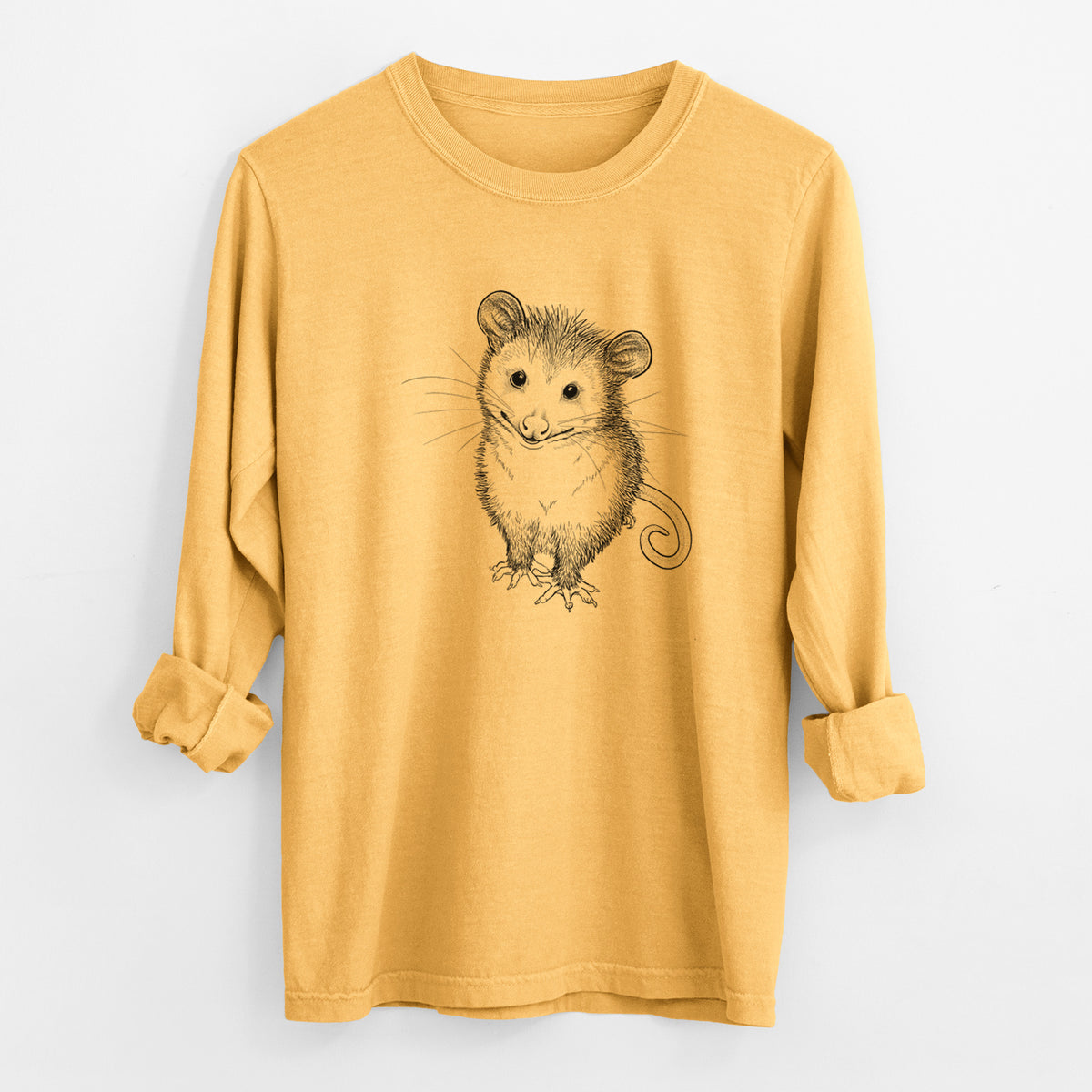 Golden wheat yellow Comfort Colors long sleeve shirt laid flat with the cuffs rolled, printed with a black ink illustration of a wide-eyed baby opossum sitting.