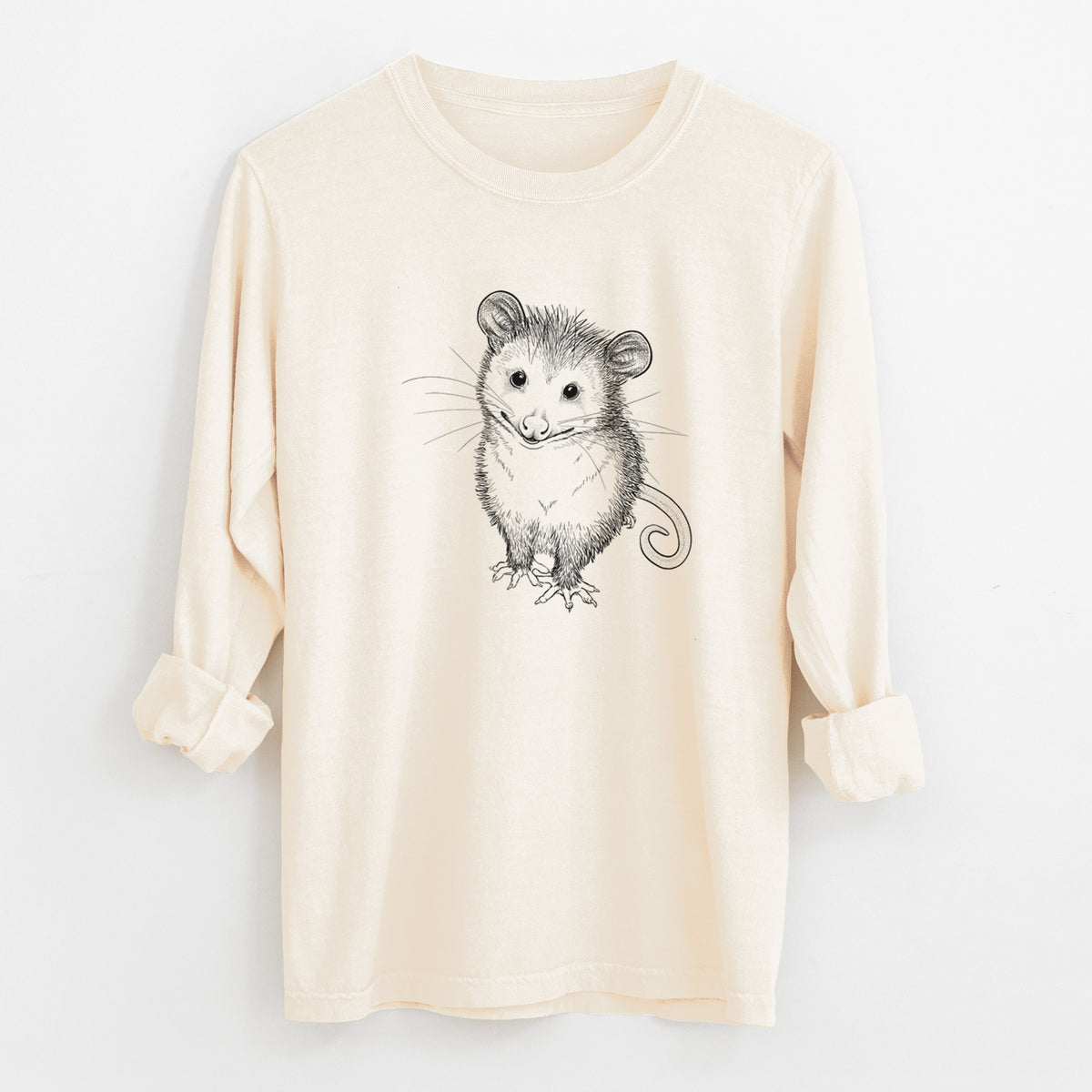 Ivory Comfort Colors long sleeve shirt laid flat with the cuffs rolled, printed with a black ink illustration of a wide-eyed baby opossum sitting.