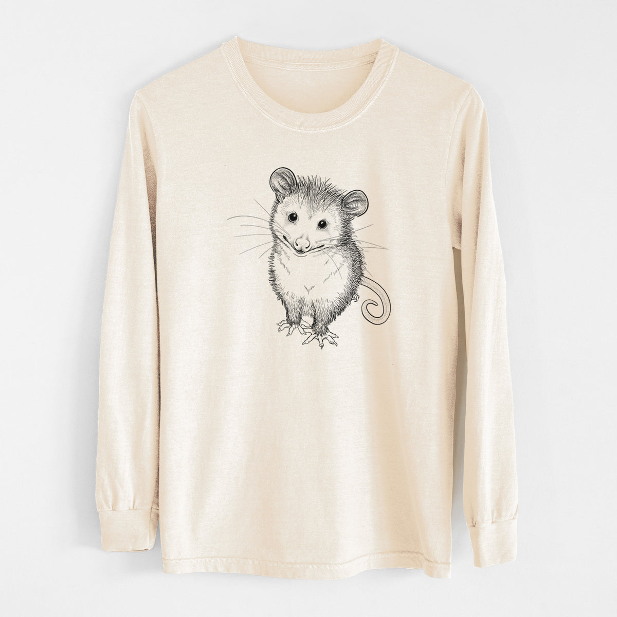 Ivory Comfort Colors long sleeve shirt laid flat, printed with a black ink illustration of a wide-eyed baby opossum sitting.