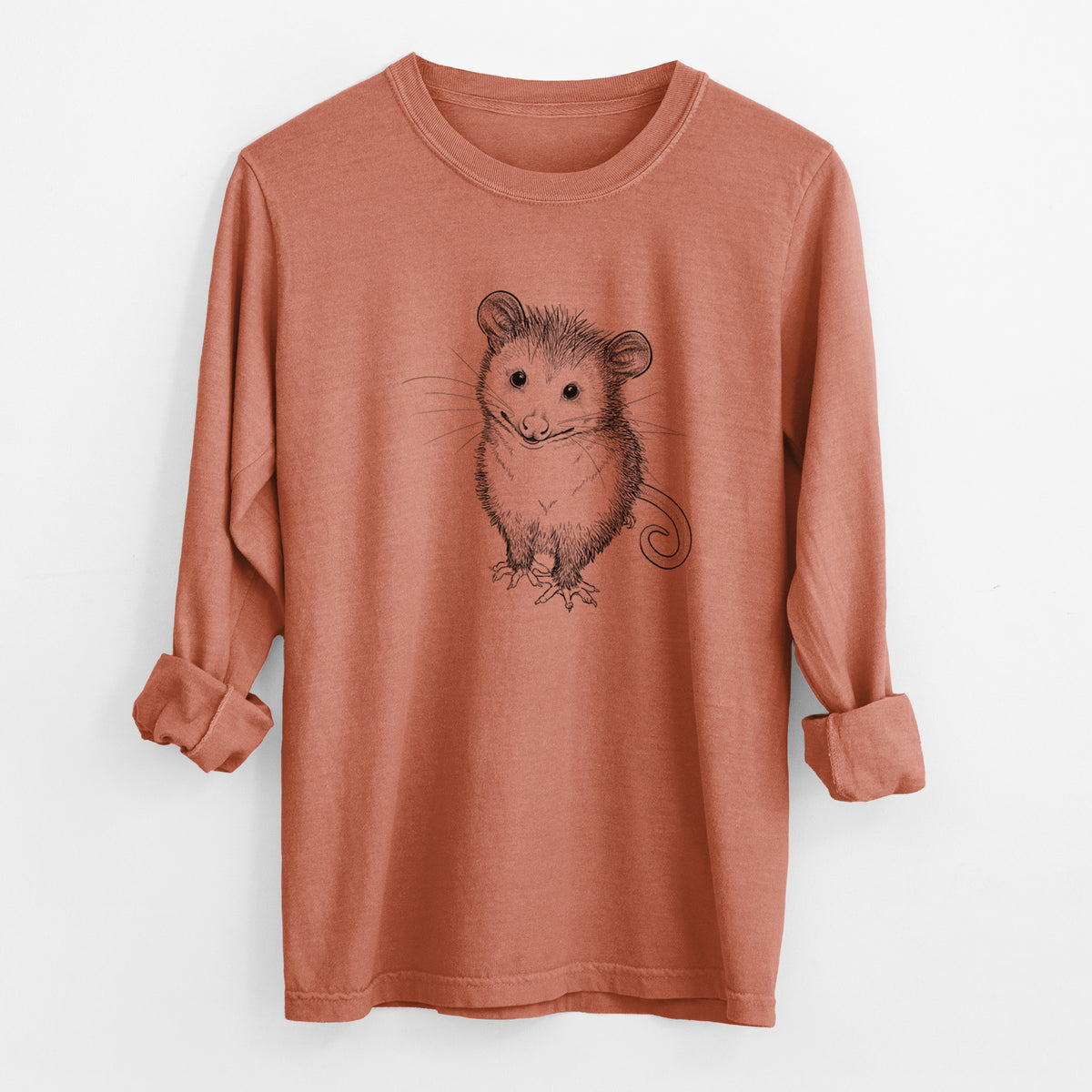 Yam burnt orange Comfort Colors long sleeve shirt laid flat with the cuffs rolled, printed with a black ink illustration of a wide-eyed baby opossum sitting.
