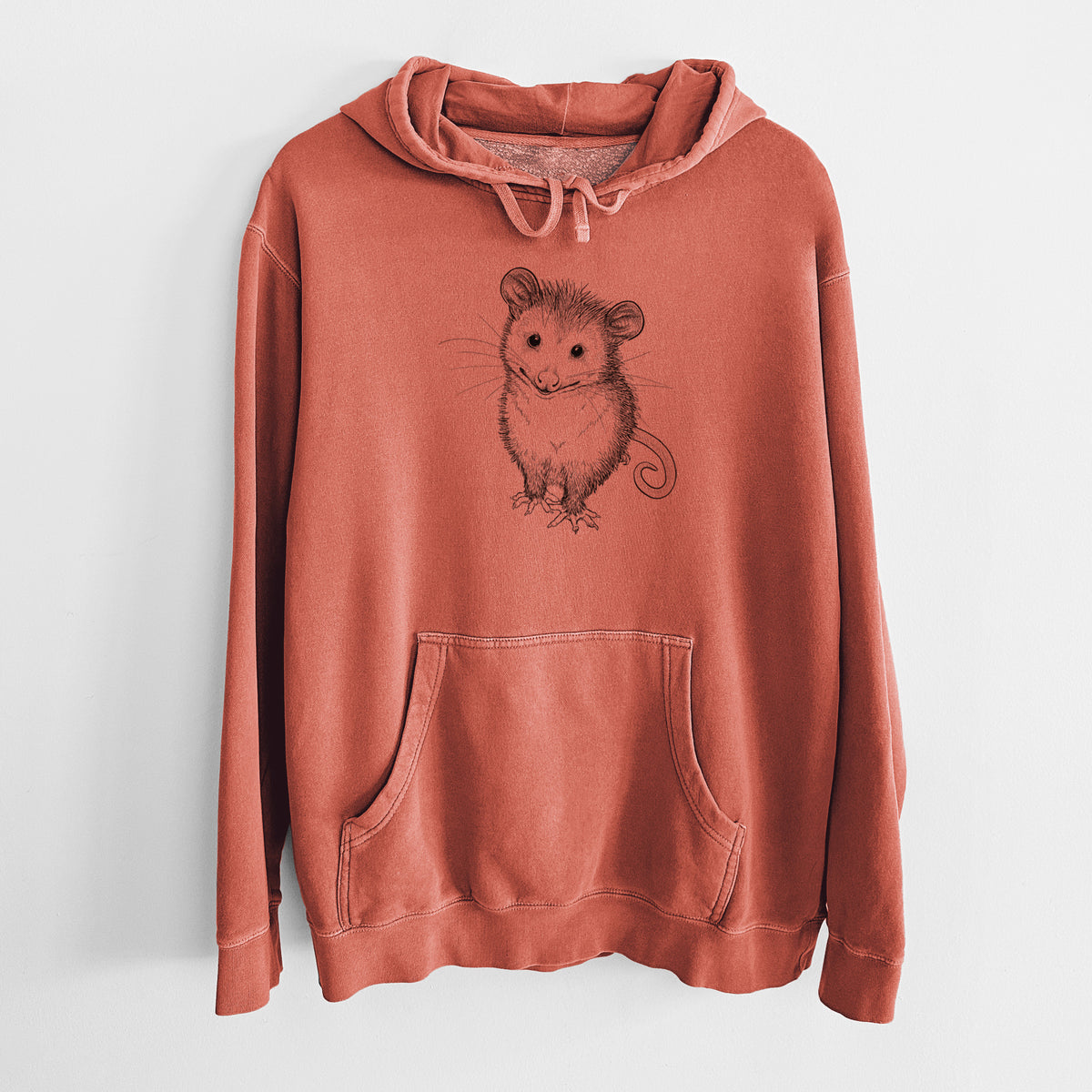 Amber orange pigment dyed hoodie laid flat, printed with a black ink illustration of a wide-eyed baby opossum sitting.