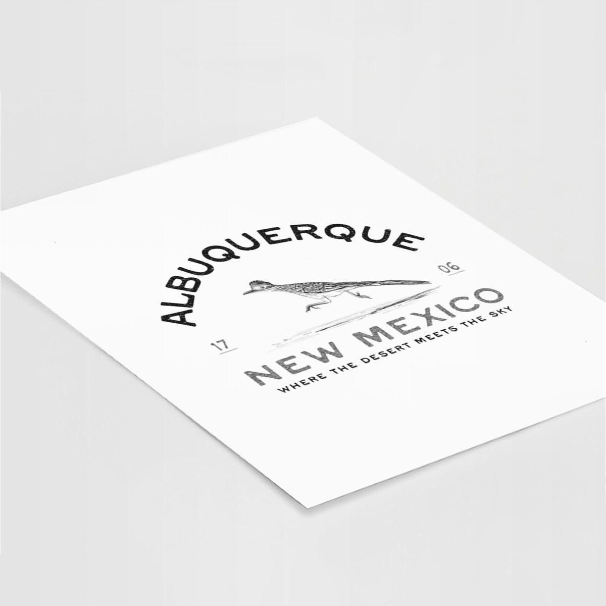 Art print of a black ink roadrunner with the words Albuquerque New Mexico, 1706, Where the Desert Meets the Sky, lying at an angle on a white surface.