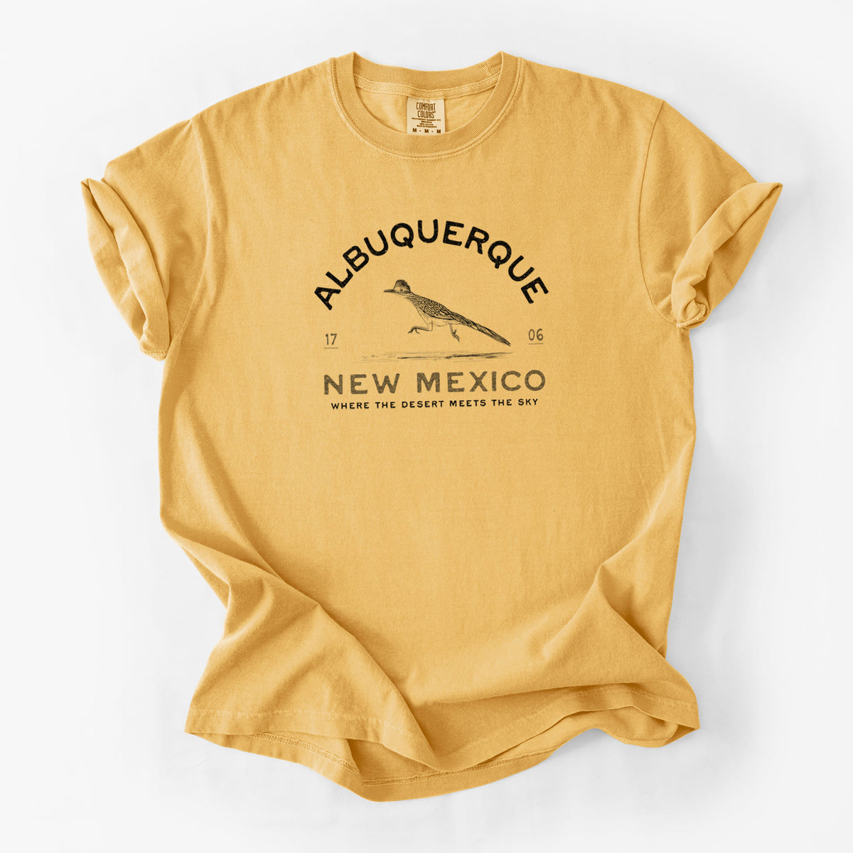 Golden wheat yellow Comfort Colors t-shirt laid flat, printed with a black ink roadrunner with the words Albuquerque New Mexico, 1706, Where the Desert Meets the Sky.