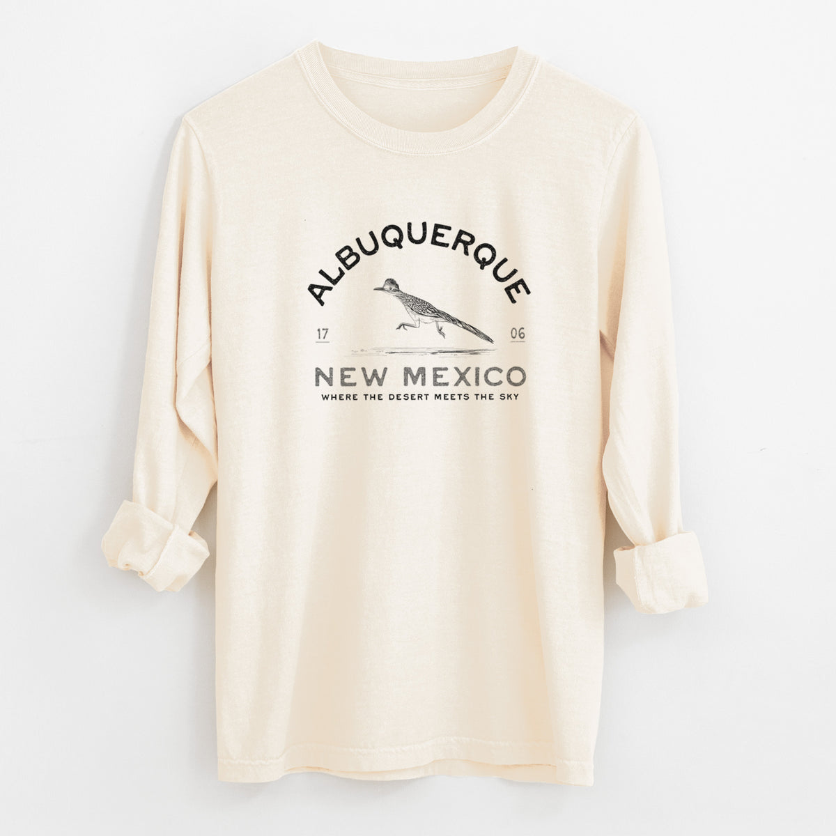 Ivory Comfort Colors long sleeve shirt laid flat with the cuffs rolled, printed with a black ink roadrunner with the words Albuquerque New Mexico, 1706, Where the Desert Meets the Sky.