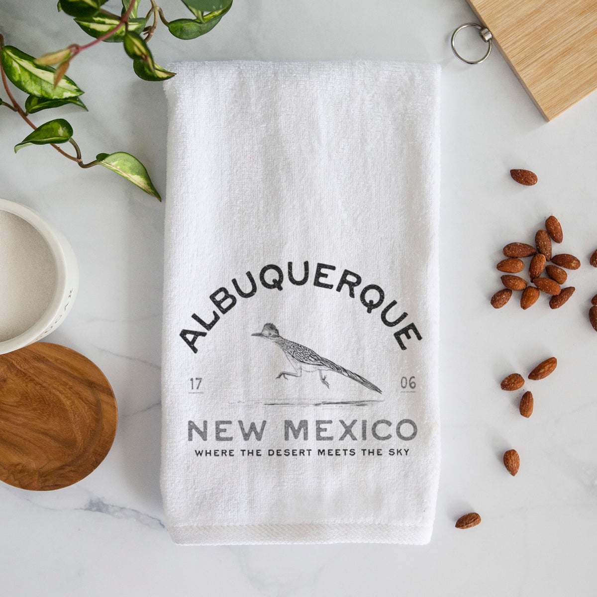 White hand towel printed with a black ink roadrunner with the words Albuquerque New Mexico, 1706, Where the Desert Meets the Sky.