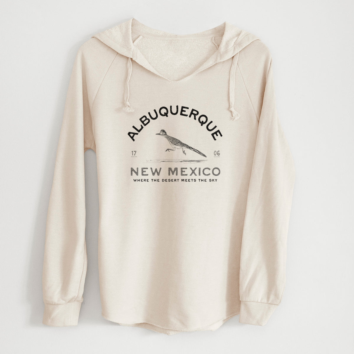 Bone cream women's Cali Wave hooded sweatshirt laid flat, printed with a black ink roadrunner with the words Albuquerque New Mexico, 1706, Where the Desert Meets the Sky.