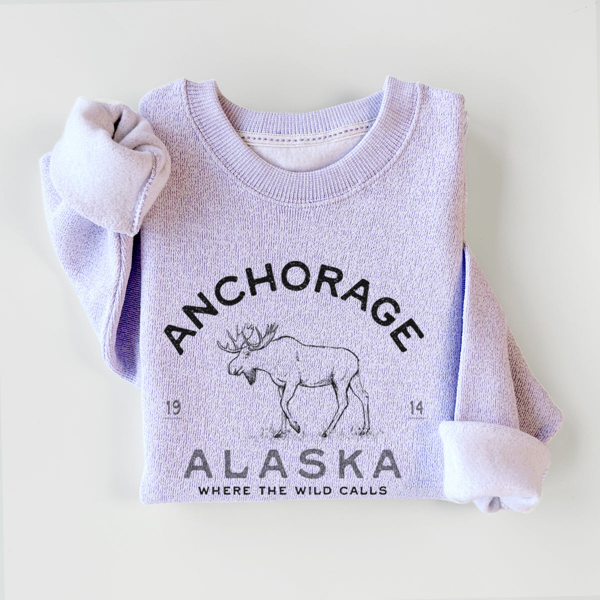 Ice purple knit sweatshirt printed with a black ink moose with the words Anchorage Alaska, 1914, Where the Wild Calls, styled flat.