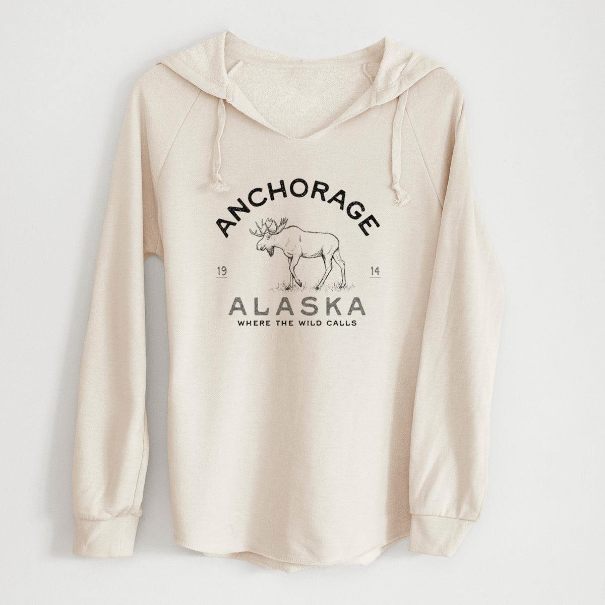 Bone cream women's Cali Wave hooded sweatshirt laid flat, printed with a black ink moose with the words Anchorage Alaska, 1914, Where the Wild Calls.