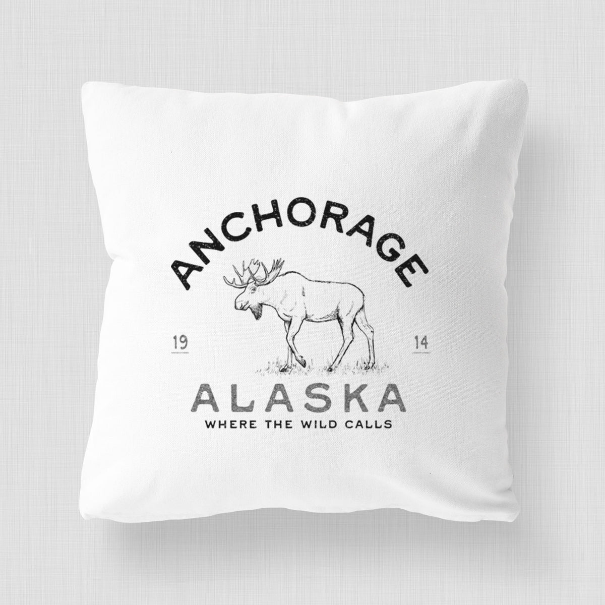 White pillow cover printed with a black ink moose with the words Anchorage Alaska, 1914, Where the Wild Calls.