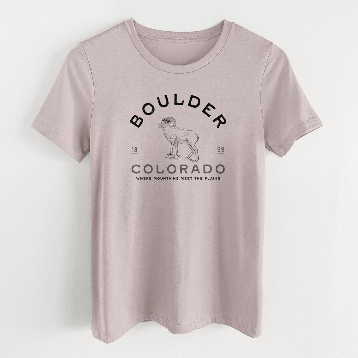 Pink gravel women's relaxed fit cotton t-shirt laid flat, printed with a black ink bighorn sheep with the words Boulder Colorado, Where Mountains Meet the Plains, 1859.