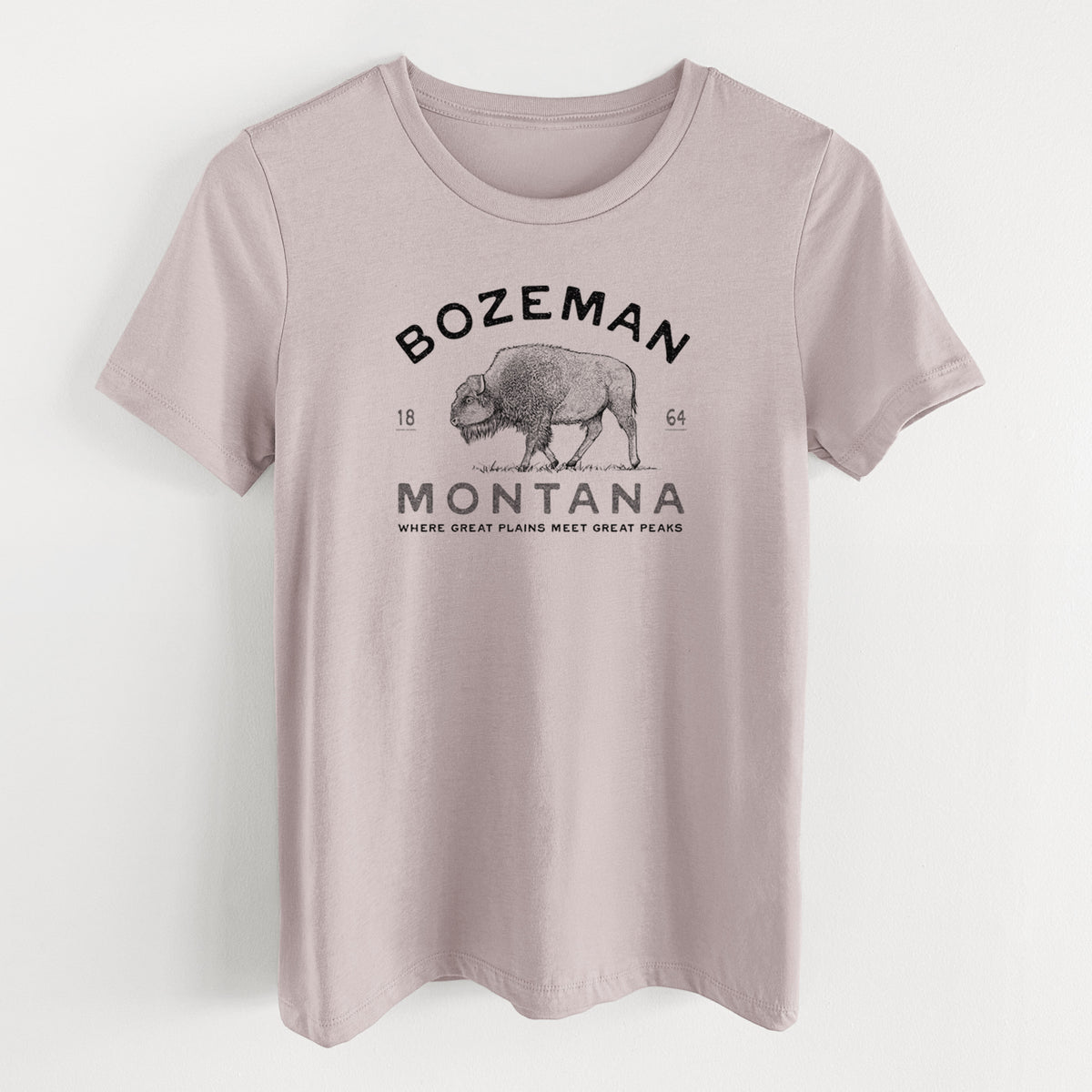 Pink gravel women's relaxed fit cotton t-shirt laid flat, printed with a black ink bison with the words Bozeman Montana, 1864, Where Great Plains Meet Great Peaks.