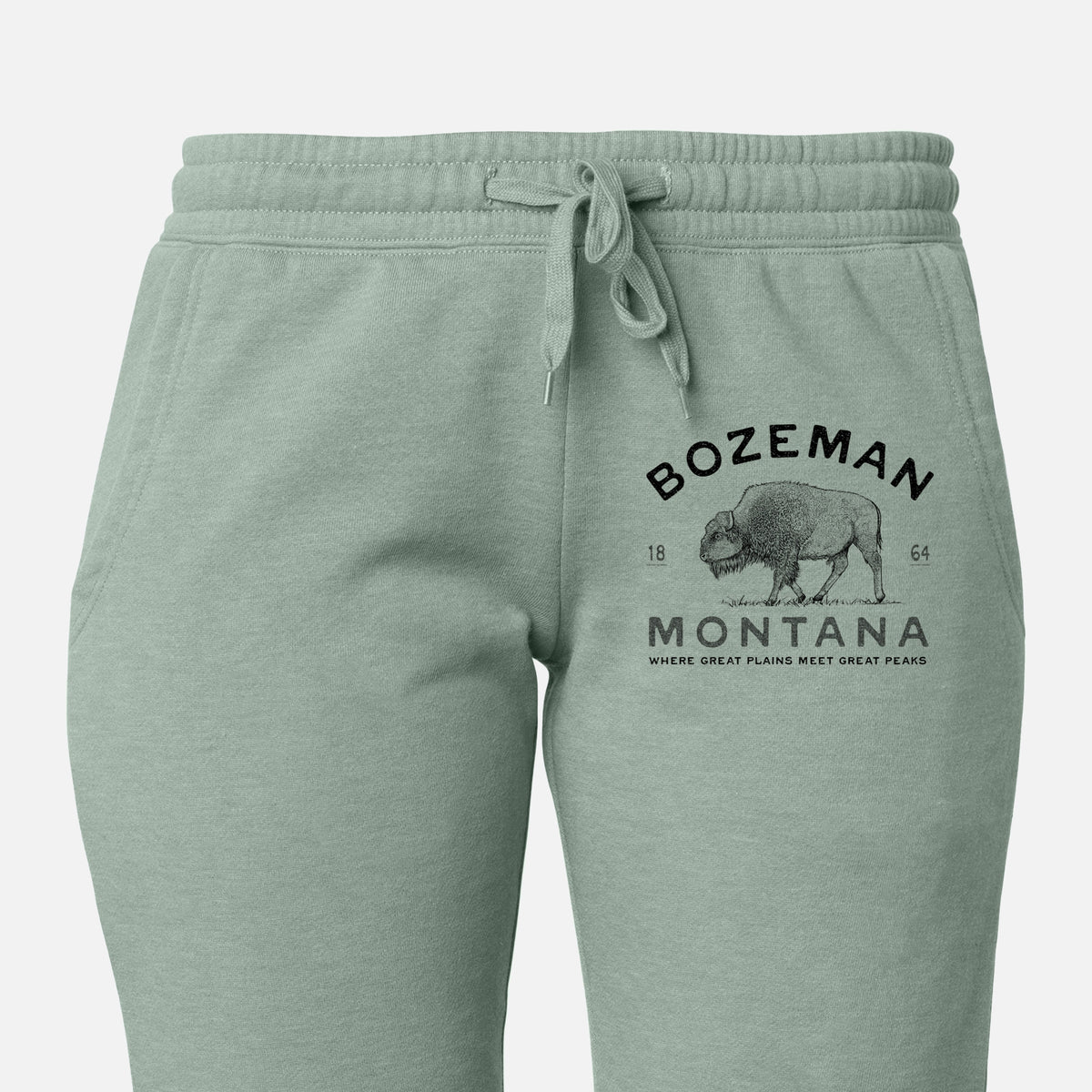 Front of sage green Cali Wave sweatpants, printed with a black ink bison with the words Bozeman Montana, 1864, Where Great Plains Meet Great Peaks on the leg.