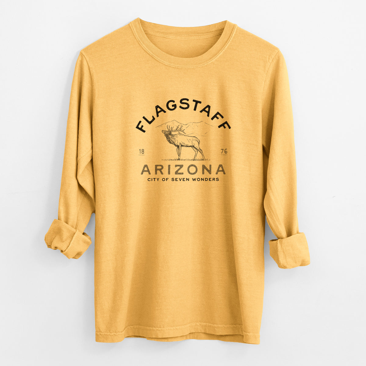 Golden wheat yellow Comfort Colors long sleeve shirt laid flat with the cuffs rolled, printed with a black ink elk with the words Flagstaff Arizona, City of Seven Wonders.