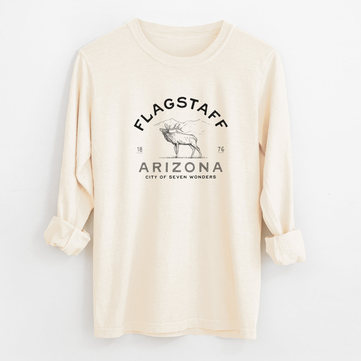 Ivory Comfort Colors long sleeve shirt laid flat with the cuffs rolled, printed with a black ink elk with the words Flagstaff Arizona, City of Seven Wonders.