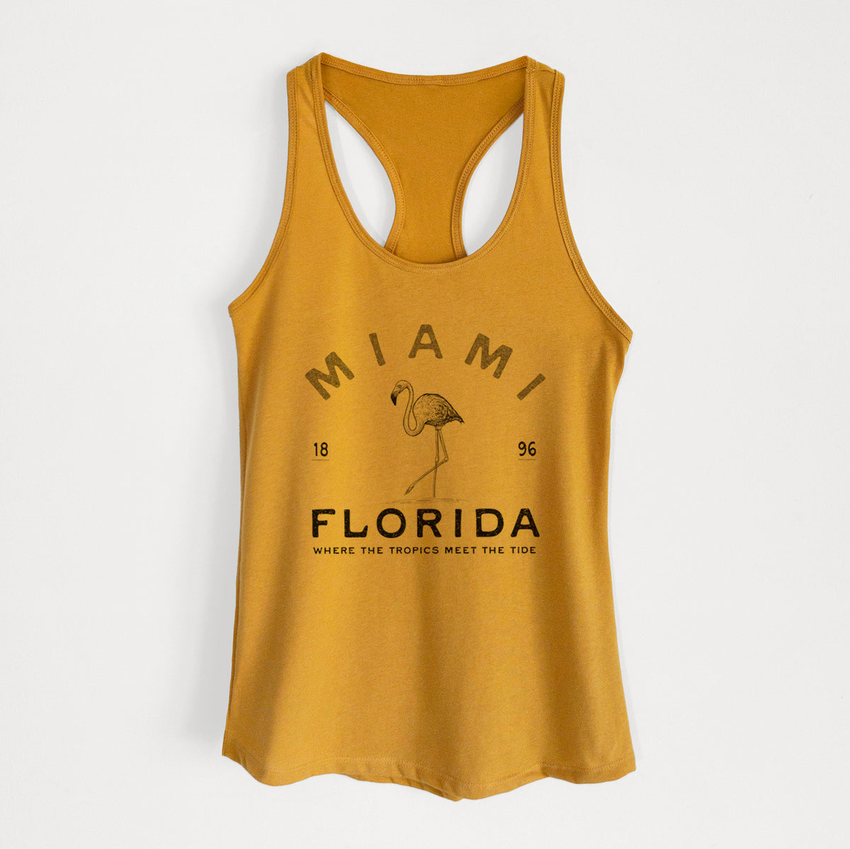 Gold women's racerback tank top laid flat, printed with a black ink flamingo with the words Miami Florida, 1896, Where the Tropics Meet the Tide.