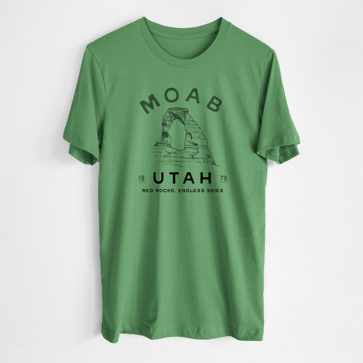 Leaf green lightweight cotton t-shirt laid flat, printed with a black ink illustration of Delicate Arch with the words Moab Utah, 1878.
