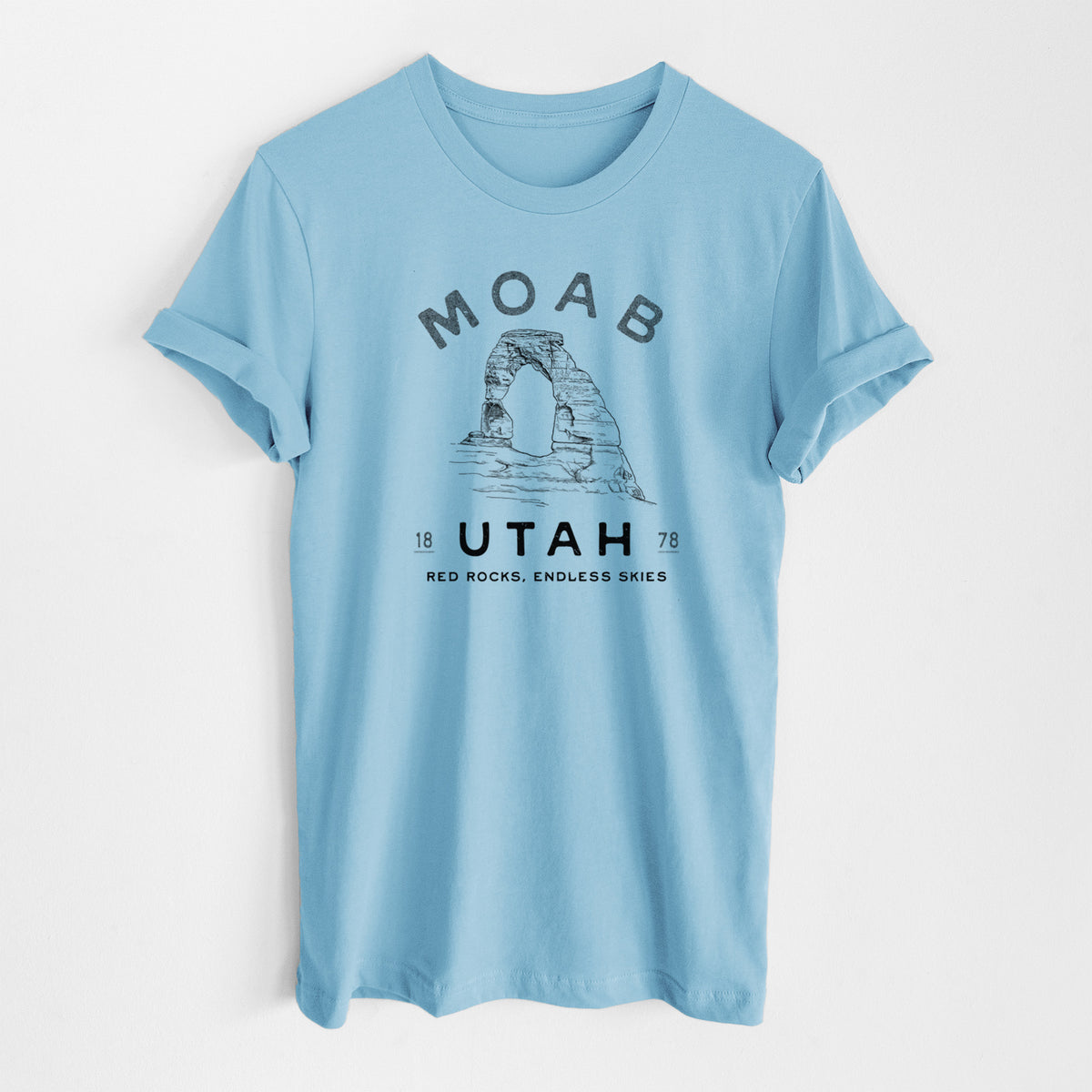 Ocean blue lightweight cotton t-shirt laid flat, printed with a black ink illustration of Delicate Arch with the words Moab Utah, 1878.