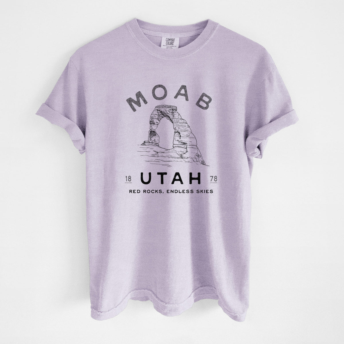 Orchid purple Comfort Colors t-shirt laid flat, printed with a black ink illustration of Delicate Arch with the words Moab Utah, 1878.
