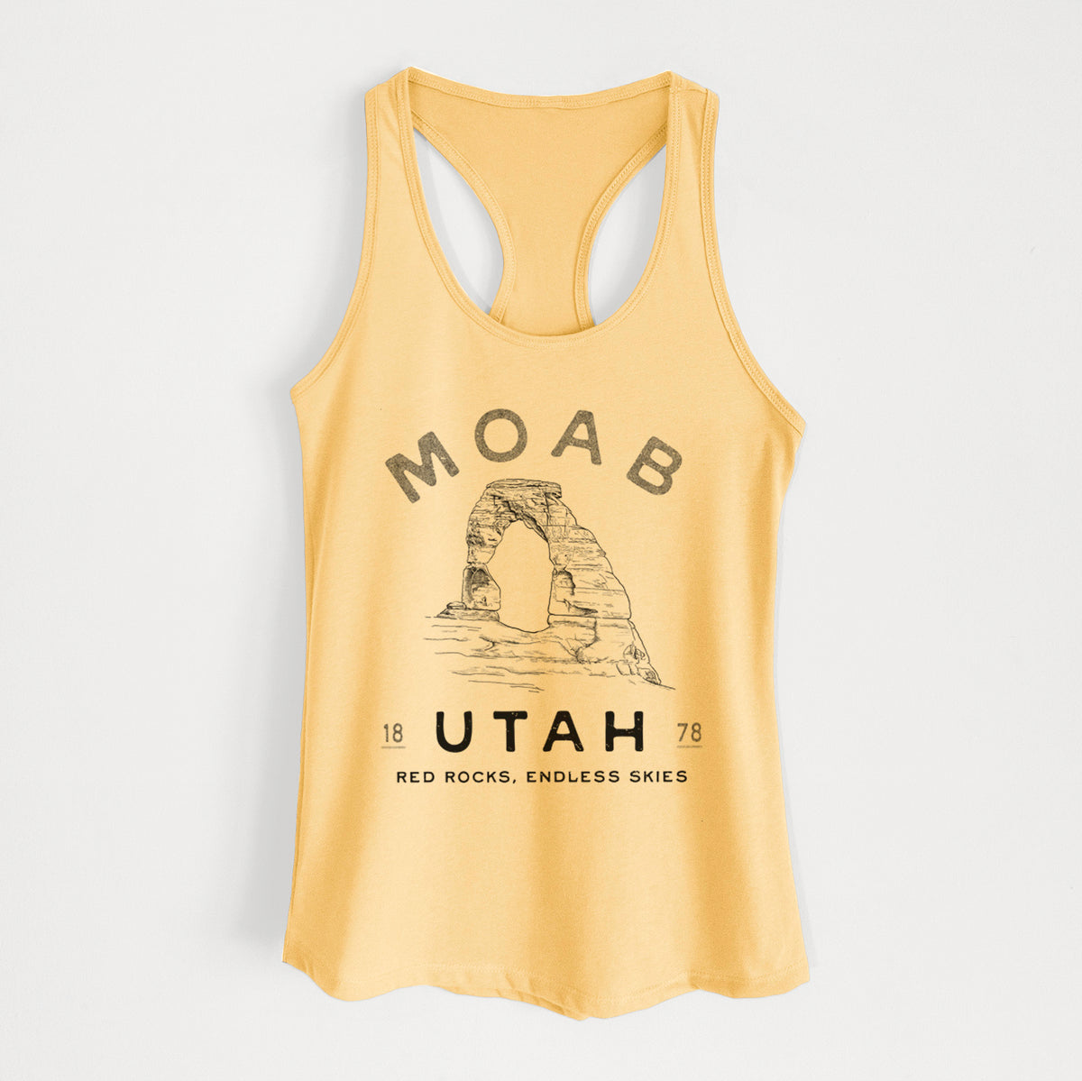 Banana cream women's racerback tank top laid flat, printed with a black ink illustration of Delicate Arch with the words Moab Utah, 1878.